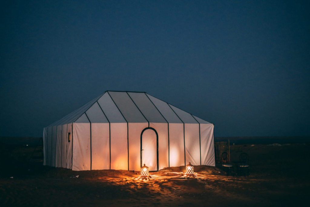 Desert camp tent glowing with lanterns at night