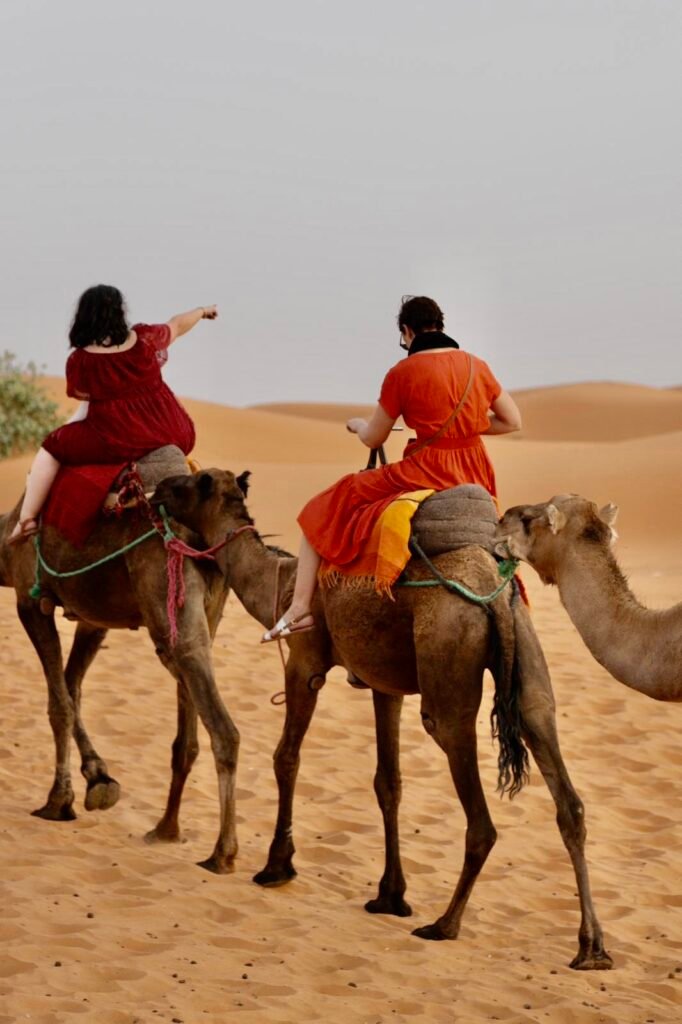 Two travelers riding camels across the Sahara dunes