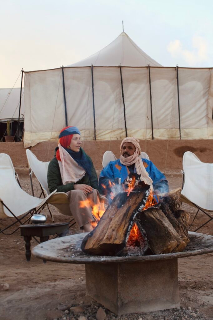 Travelers sharing tea with a Berber host at a desert camp